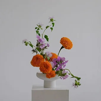 White and pink floral arrangements in ceramic pitchers against a deep green wall